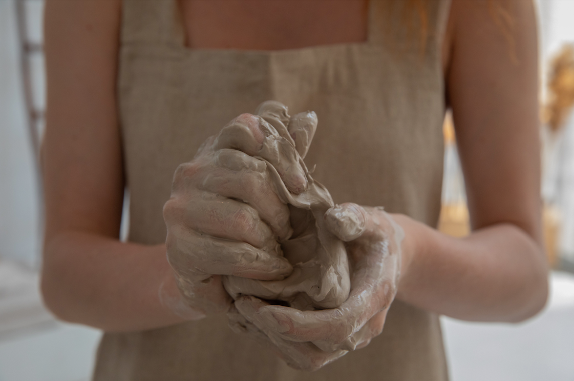 Hands holding a mound of clay.
